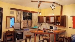 Une cuisine de taille réduite équipée d’une cuisinière à gaz, d’un four, d’un four à micro-ondes et de meubles de rangement en bois.