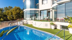 Una casa moderna con piscina, ampie finestre e un prato ben curato.