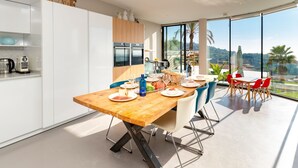 Una cucina moderna con mobili bianchi, un tavolo da pranzo in legno e vista sull'esterno.