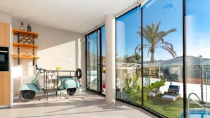 Un interno moderno con uno scooter, ampie finestre e vista su una piscina.