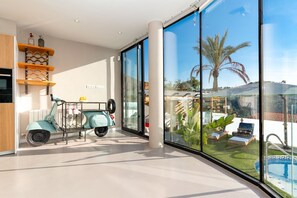 Ein modernes Interieur mit einem Roller, großen Fenstern und Blick auf einen Pool.