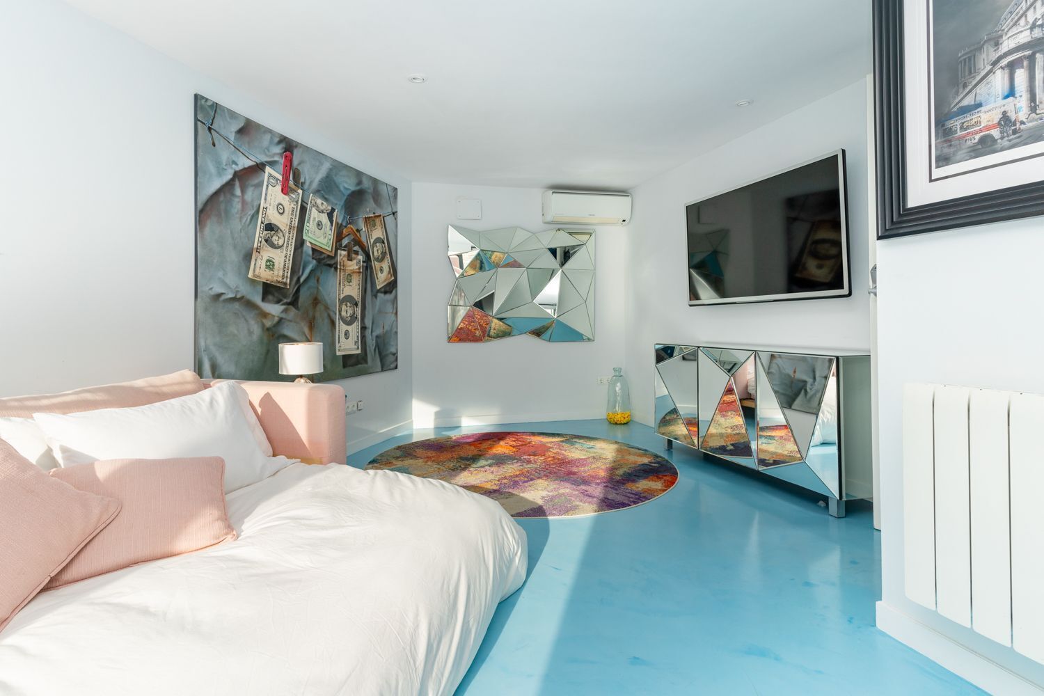 Une chambre à coucher avec un lit, un tapis rond, un miroir et un téléviseur.
