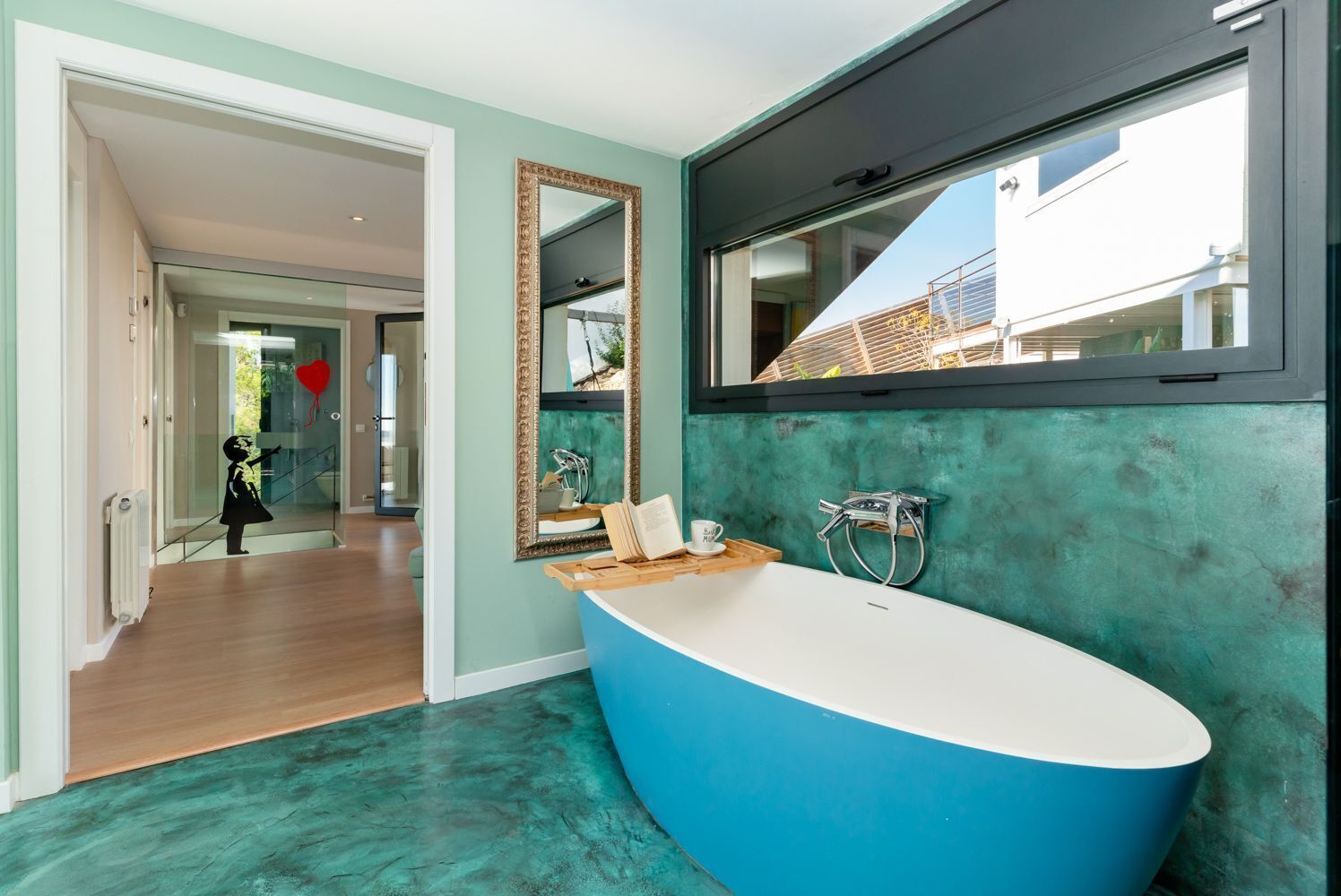 A modern bathroom with a large freestanding bathtub, a mirror, and a view of the outside.
