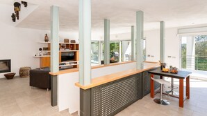 Et moderne køkken med træbordplade, spiseområde med bord og stole, samt et fjernsyn på en hylde.