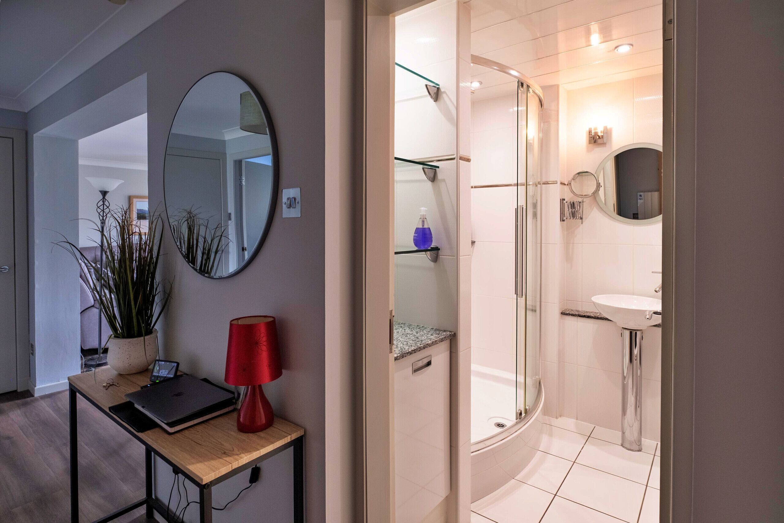 Une salle de bain moderne avec une douche à parois de verre, un lavabo et un miroir.