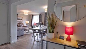 Ein modernes Wohnzimmer mit Essbereich, einem großen Spiegel und einer roten Lampe.