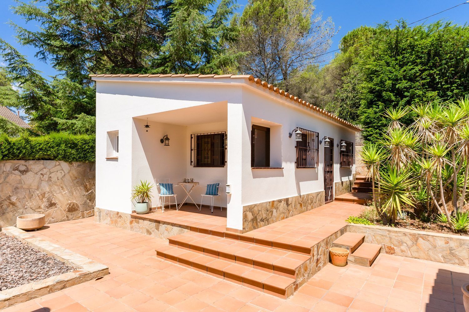 Un edificio blanco con un patio, escalones y un muro de piedra.