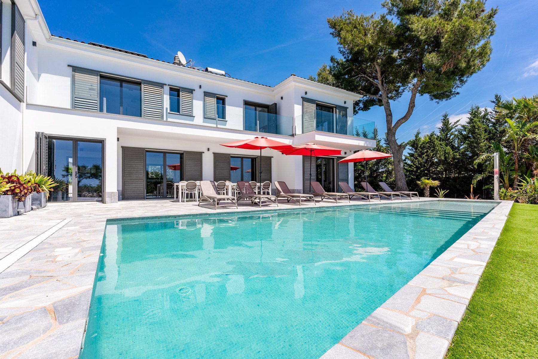 A modern house with a swimming pool, outdoor seating, and a well-maintained lawn.