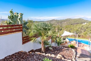 A pool area with a view of hills, a palm tree, and cacti. - Villa Moments - Four Bedroom Villa, Sleeps 10 (Vora-sitges)