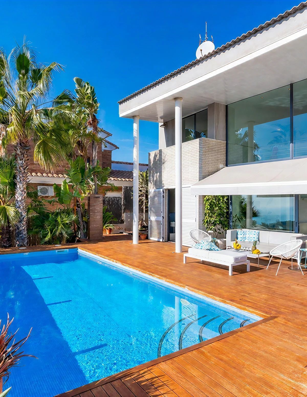 A modern house with a swimming pool, outdoor furniture, and lush greenery.
