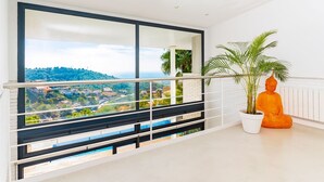Ein Balkon mit Blick auf eine Stadt, einer Topfpflanze und einer Buddha-Statue.