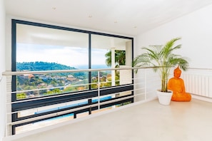 Ein Balkon mit Blick auf eine Stadt, einer Topfpflanze und einer Buddha-Statue.