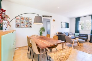 Ein moderner Wohnraum mit Holztisch, gemütlichen Sitzgelegenheiten, einer Couch und einer Wandleuchte.