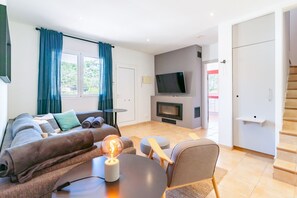 Ein modernes Wohnzimmer mit einer Couch, einem Couchtisch, einem Fernseher und einem Kamin.
