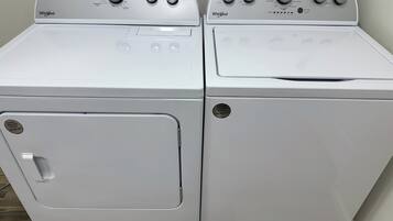 Zwei weiße Whirlpool Waschmaschinen mit Frontlader, Bedienfeldern, Türgriffen und einem Aufkleber mit einer Telefonnummer.