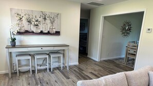 A living room with a sofa, a dining area with a table and chairs, and a hallway leading to another room. - Charming 2BR Cottage - Short walk to Missouri Star & Downtown Hamilton (Hamilton)