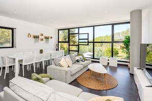 Ein modernes Wohnzimmer mit Essbereich, großen Fenstern und Blick ins Grüne.