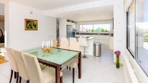 A modern kitchen with a large window, a dining area with a glass table, and a minimalist decor.