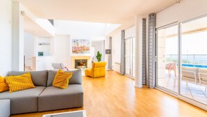 A modern living room with a grey sofa, yellow cushions, a glass coffee table, and a fireplace.