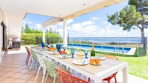 An outdoor dining area with a pool view, a grill, and colorful chairs.