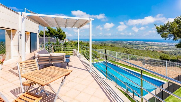 A rooftop terrace with a pool, outdoor seating, and a view of the landscape.