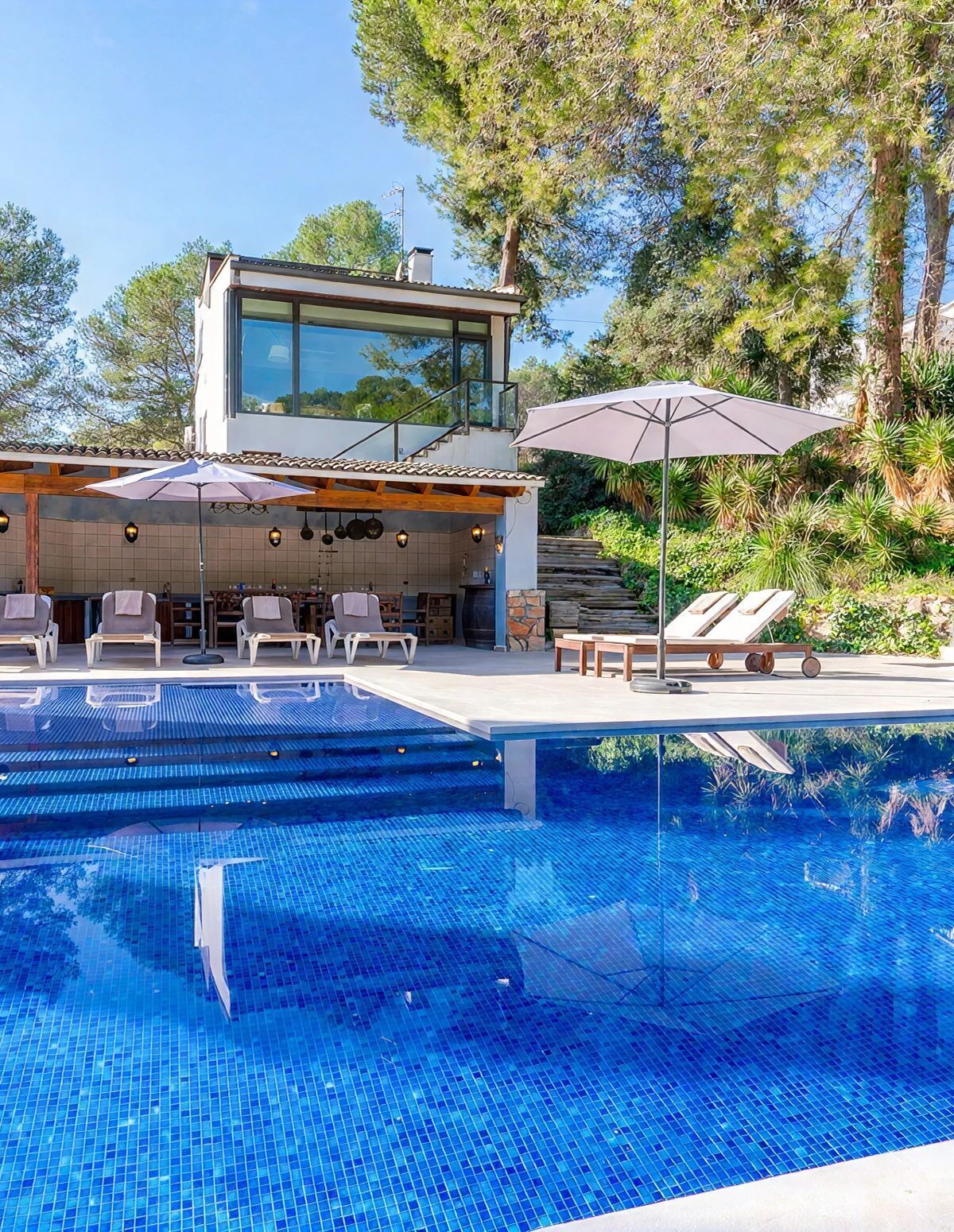 Ein moderner Poolbereich im Freien mit Liegestühlen und einer Grillgelegenheit.