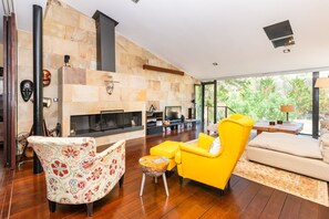 Ein modernes Wohnzimmer mit Kamin, einem gelben Sessel, einem gemusterten Sessel und einer Couch.