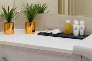 A bathroom with a white countertop, two potted plants, and toiletries. - Pollen Spacious 2-bedroom Apartment in Mayfair (London)