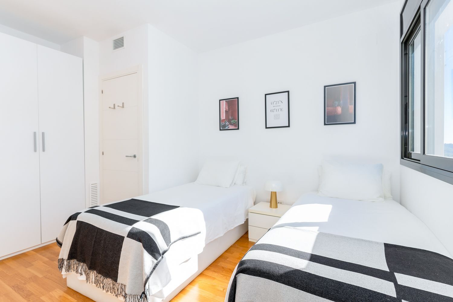 Een slaapkamer met twee bedden, een kast en een raam.