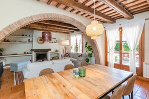 Ein gemütliches Wohnzimmer mit Kamin, ein Essbereich mit Holztisch und eine Treppe, die zu einem Außenbereich führt.