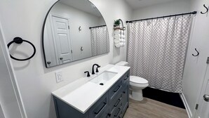 A bathroom with a white sink, a mirror, a toilet, and a shower curtain.