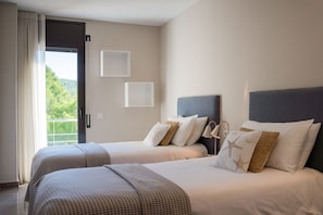 Ein Hotelzimmer mit zwei Betten, einem Balkon und Blick auf Grünflächen.