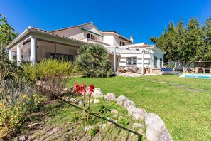 Una casa moderna con un amplio patio, piscina y jardín bien cuidado.