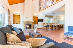 Ein geräumiger Wohnbereich mit Kamin, Esstisch und Sofa.
