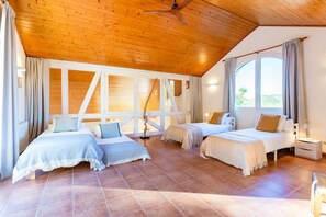 Ein Zimmer mit zwei Betten, einem Deckenventilator und einem großen Fenster.
