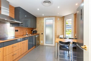 A modern kitchen with grey cabinets, a wooden countertop, and a built-in dishwasher. - Apartment Tropicana - Three Bedroom Apartment, Sleeps 6 (Sitges)