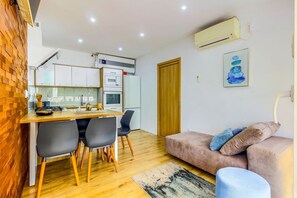 A compact living space with a kitchenette, dining area, and a sofa.