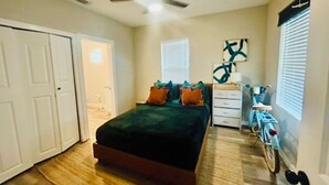 A bedroom with a bed, a dresser, a bicycle, and a ceiling fan. - Stylish Downtown Cottage near Alamodome, Hemisphere & Riverwalk (San Antonio)