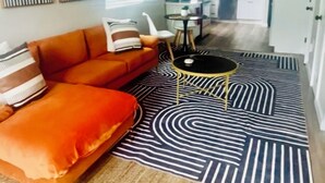 A living room with a sofa, a coffee table, and a kitchen in the background. - Stylish Downtown Cottage near Alamodome, Hemisphere & Riverwalk (San Antonio)
