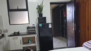 Een hotelkamer met een bed, een bureau, een koelkast, een kamerplant en een kledingkast.