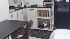 Een kleine keuken met een koelkast, fornuis en een eethoek.