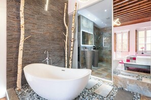 Un baño moderno con una bañera independiente, ducha con mampara de vidrio y tocador con espejo.