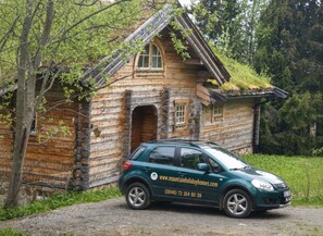 A log cabin with a car parked in front, surrounded by trees. - Mountain Holiday Homes (Undersaker)
