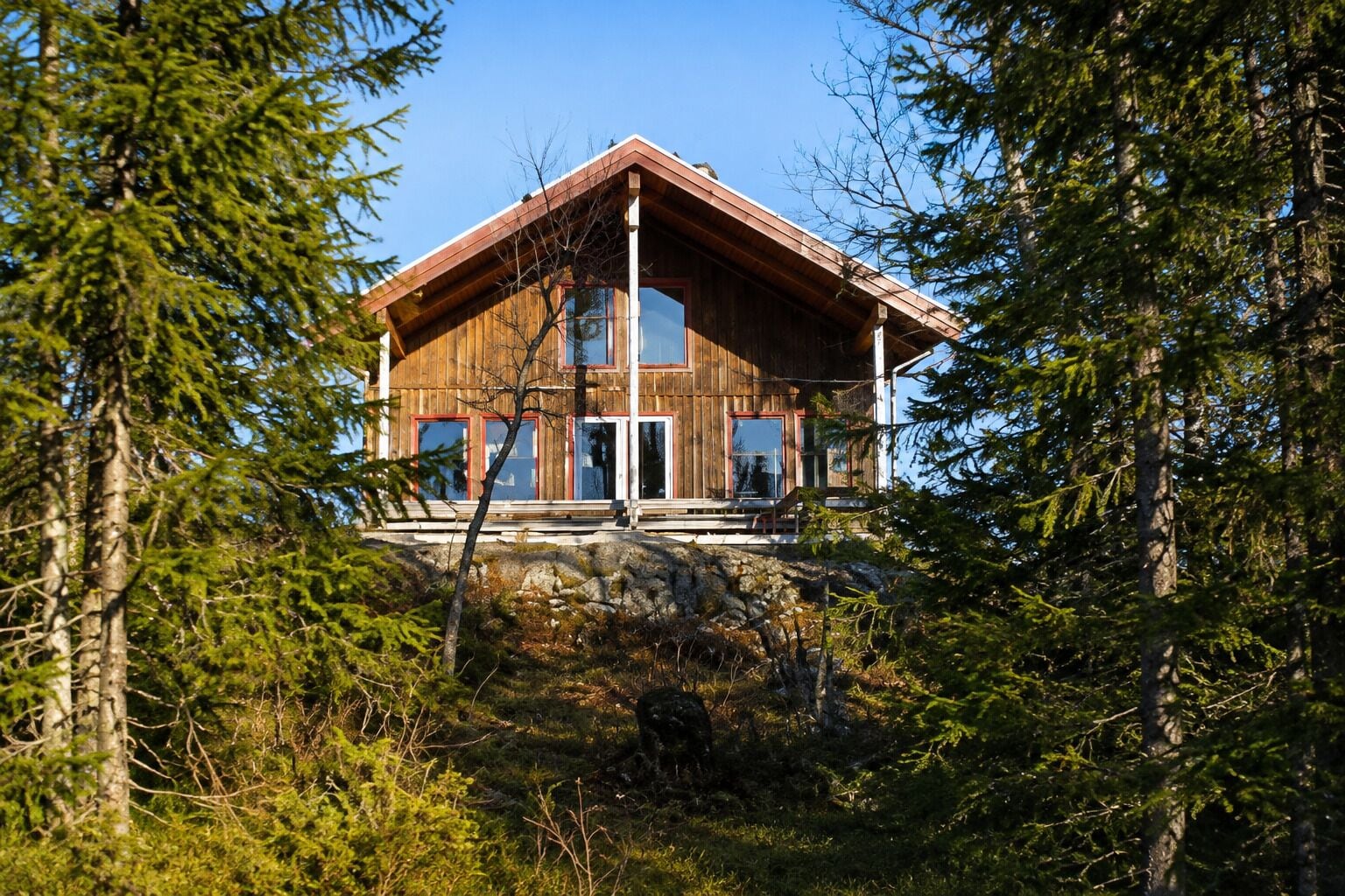 Una cabaña de madera con cimientos de piedra, rodeada de un bosque denso.