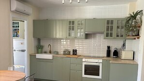 Une cuisine moderne avec des meubles de couleur verte, un four encastré et un coin repas comprenant une table ronde et des chaises.