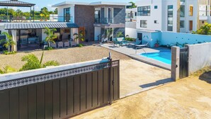 A modern residential property with a swimming pool, outdoor seating, and a gated entrance.