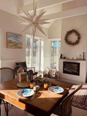 A dining area with a wooden table, chairs, a fireplace, and a ceiling fan.