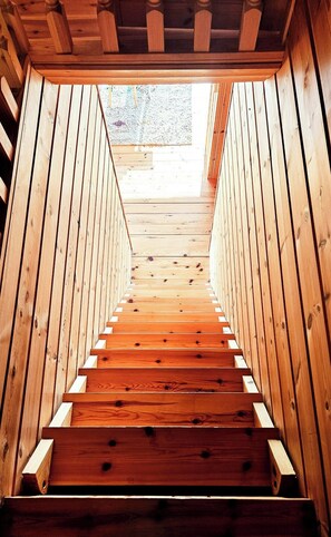 Eine Holztreppe führt zu einem Außenbereich mit Blick auf einen Garten.
