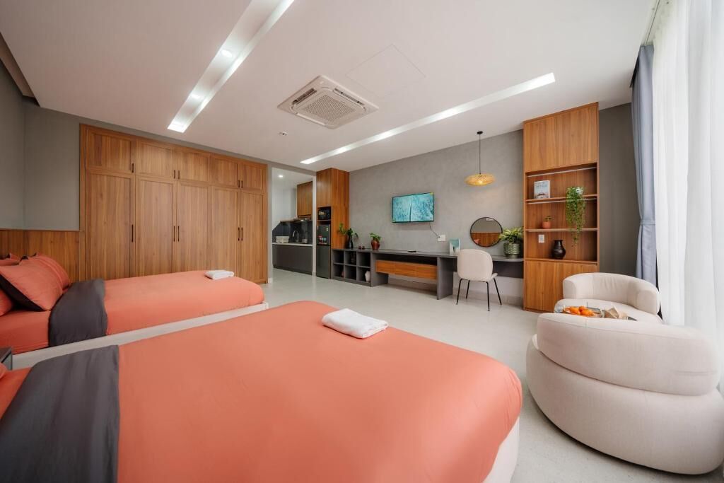 A modern hotel room with two beds, a desk, and a seating area.