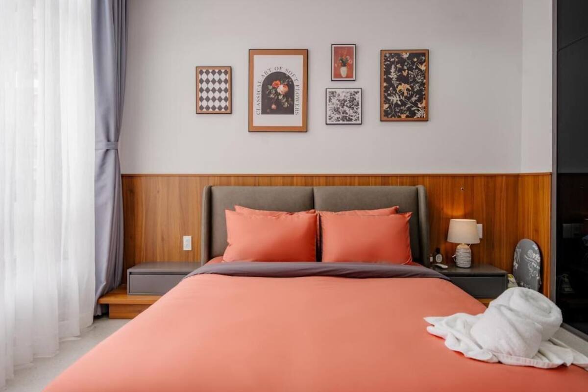 A hotel room with a bed, a nightstand, a lamp, and a framed picture on the wall.